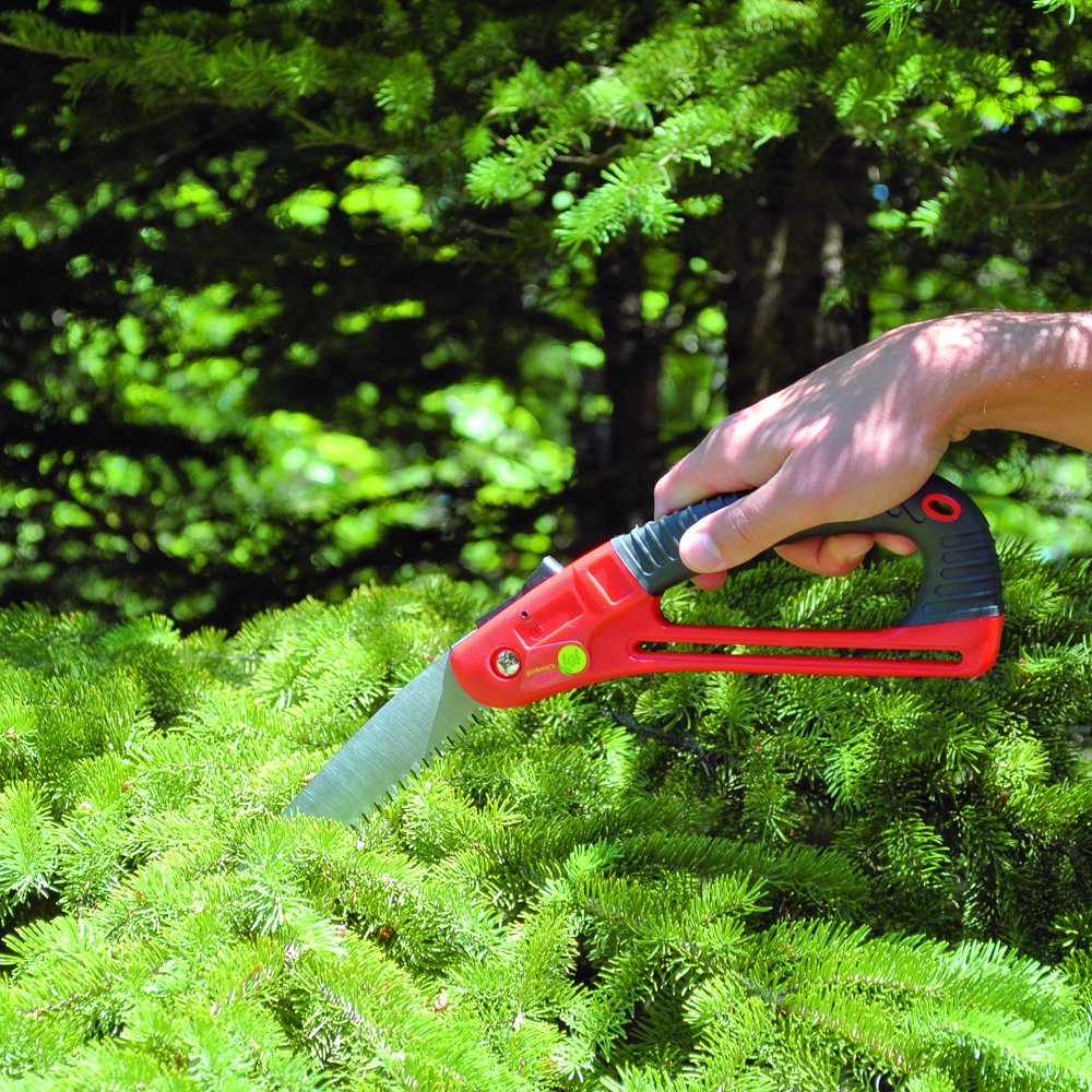 hand holding a pruning saw cutting down a bush